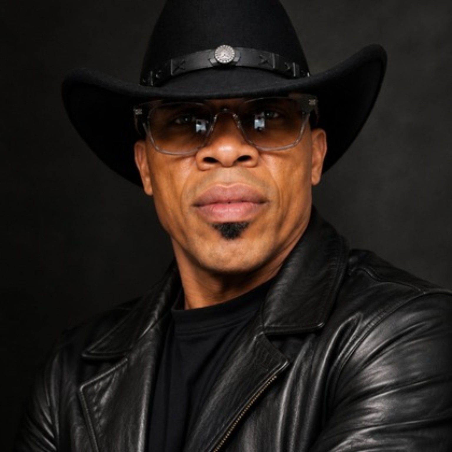 Devron Blaze in a black cowboy hat, glasses, and leather jacket
